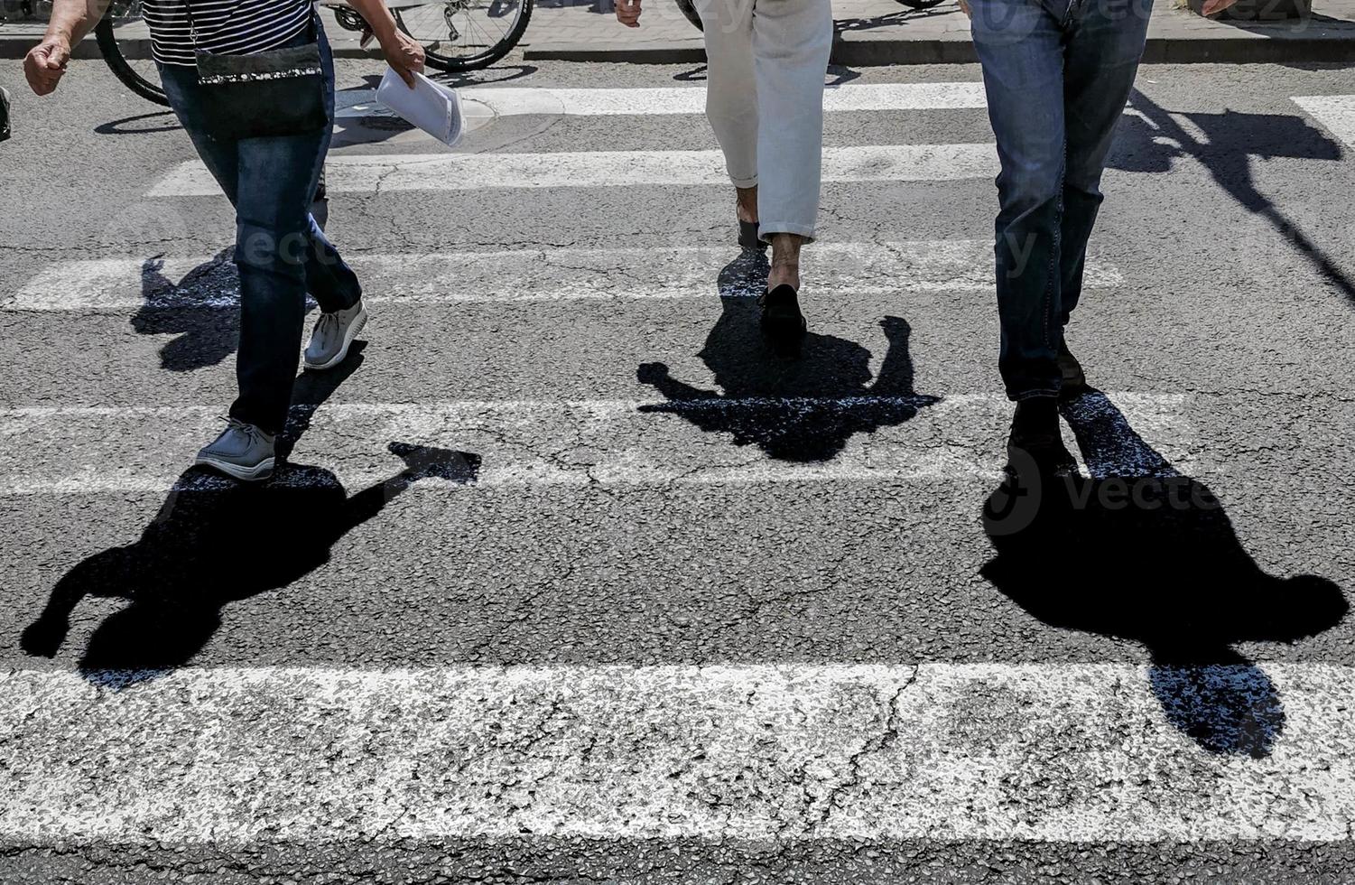 passagem de pedestres com as sombras das pessoas atravessando foto