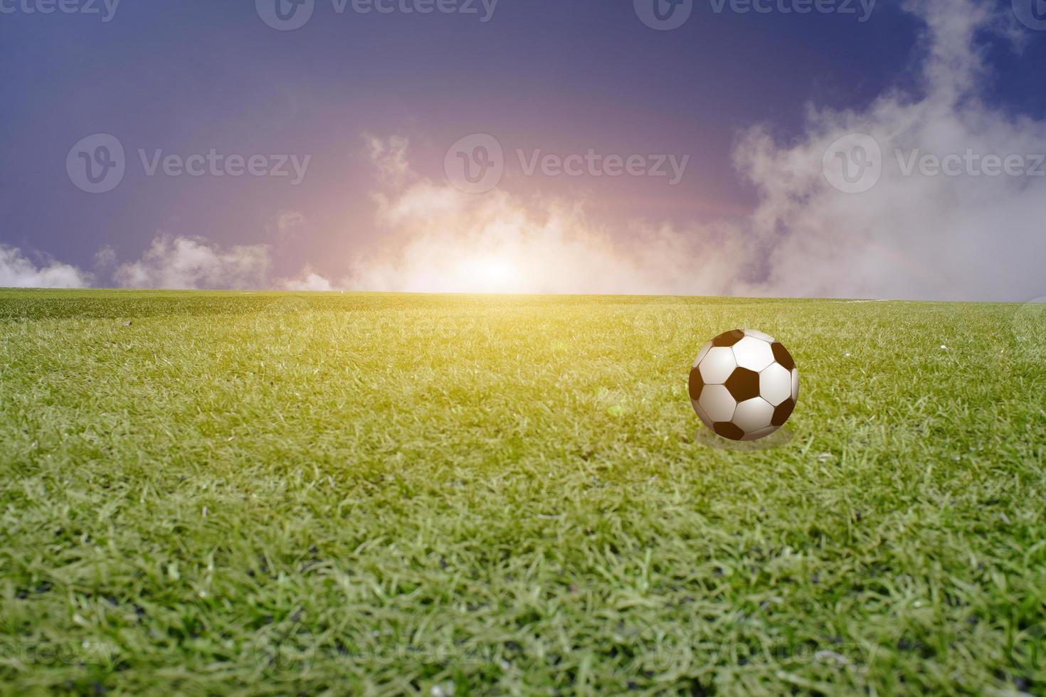 uma bola no campo verde com um pôr do sol de céu azul. pôr do sol de futebol, futebol no conceito de pôr do sol. foto