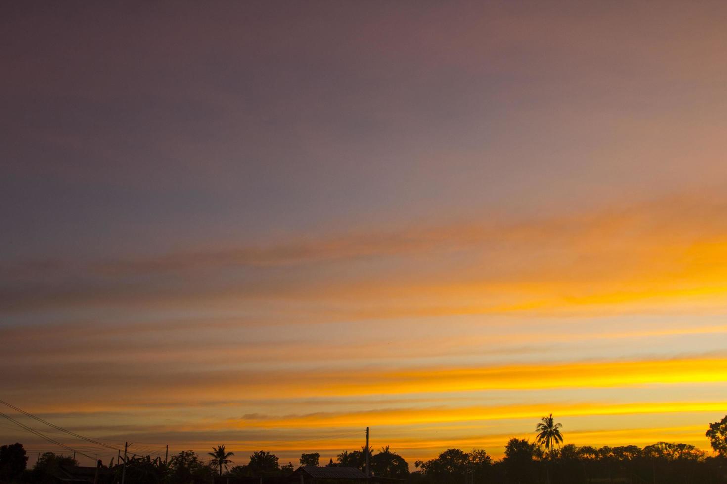 o céu é uma linha horizontal de amarelo-laranja e cores coloridas no lindo entardecer no meio da natureza que é tranquila, quente e romântica no campo e é extremamente bonita. foto