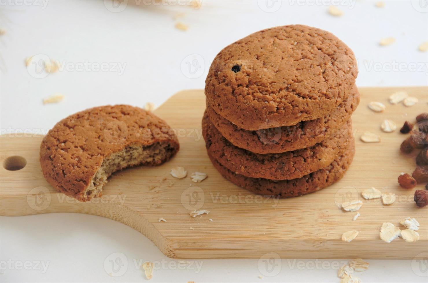 biscoitos em uma placa de madeira ao lado de passas e aveia crua, o conceito de biscoitos de aveia com passas. foto de alta qualidade