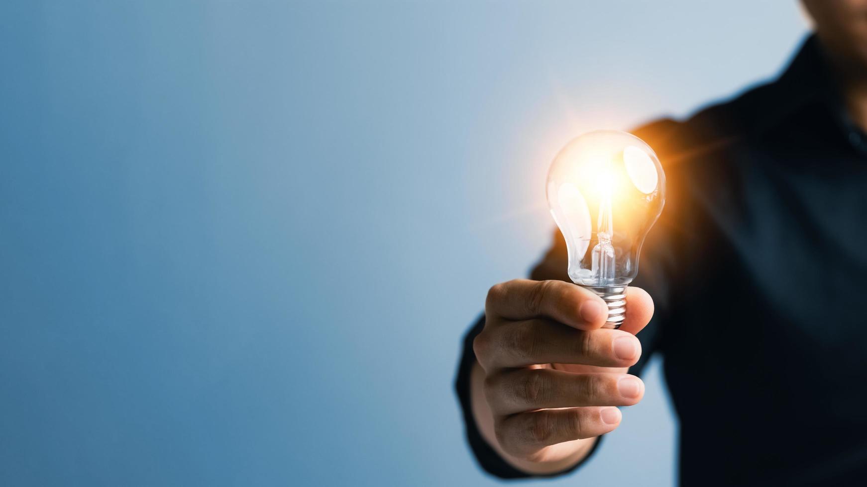 inovação bem sucedida através de ideias e ideias de inspiração. mão humana segurando a lâmpada para iluminar, ideia de criatividade e conceito de inspiração de desenvolvimento de negócios sustentáveis. foto