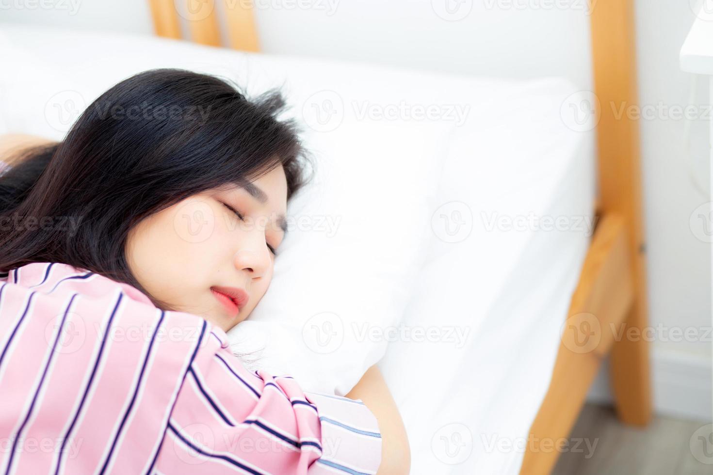 retrato da bela jovem asiática dormir deitada na cama com a cabeça no travesseiro confortável e feliz com lazer, garota com relaxar para o conceito de saúde e estilo de vida. foto