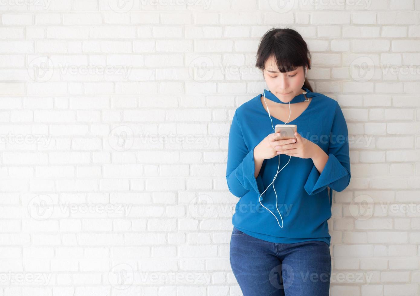 belo retrato asiático jovem em pé feliz desfrutar e diversão ouvir música com fone de ouvido no fundo de concreto de cimento, estilo de vida da menina relaxar rádio de som com fone de ouvido, conceito de tecnologia. foto