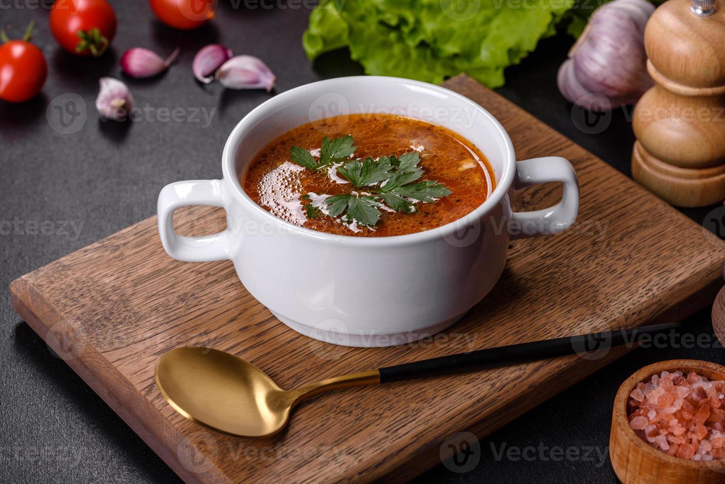 sopa de tomate fresco delicioso com especiarias e salsa em uma tigela branca em uma placa de madeira foto