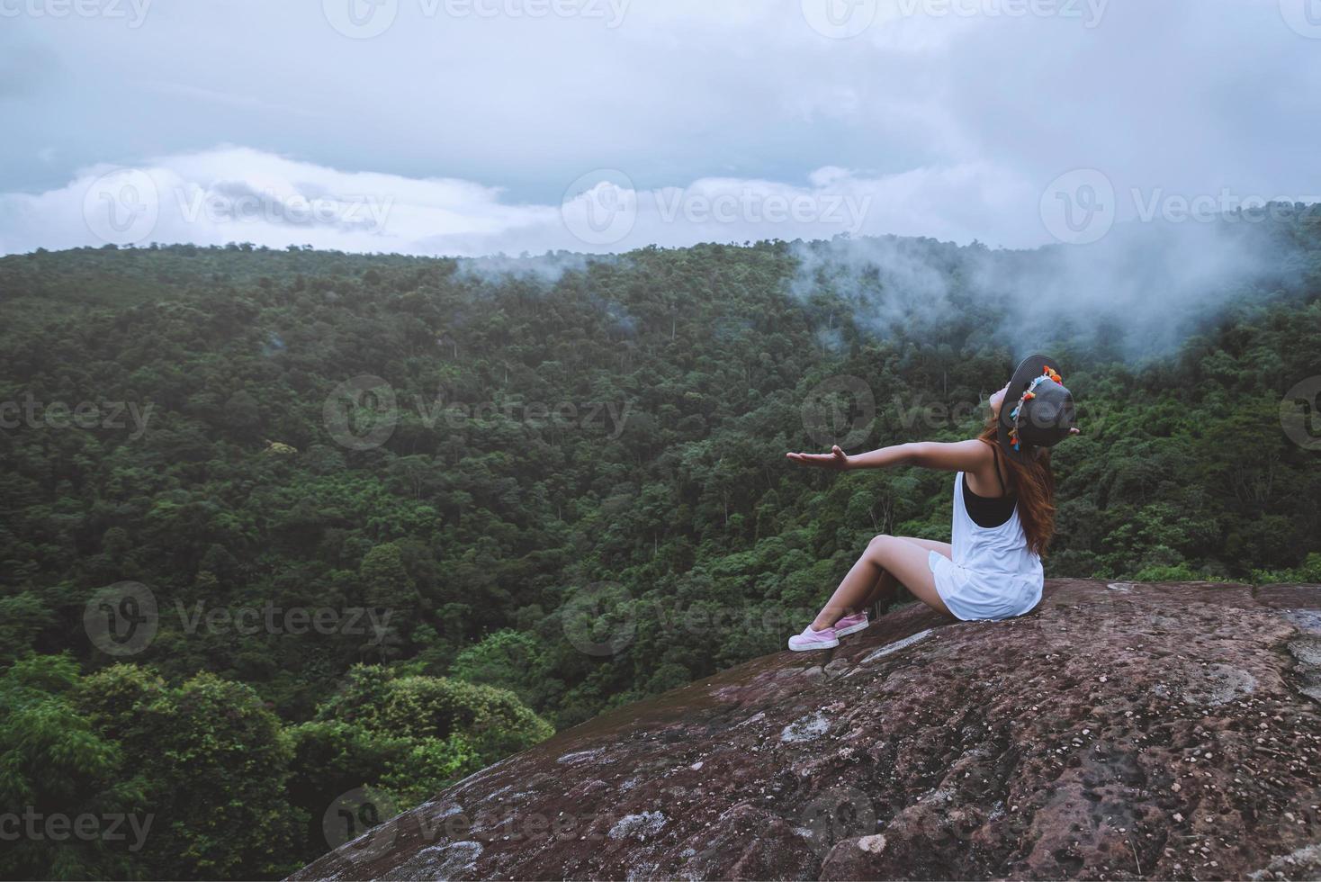 mulher asiática viajar natureza. viajar relaxar. liberdade mulher viajante feliz em pé com os braços erguidos e desfrutando de uma bela natureza no pico da montanha nebulosa. foto