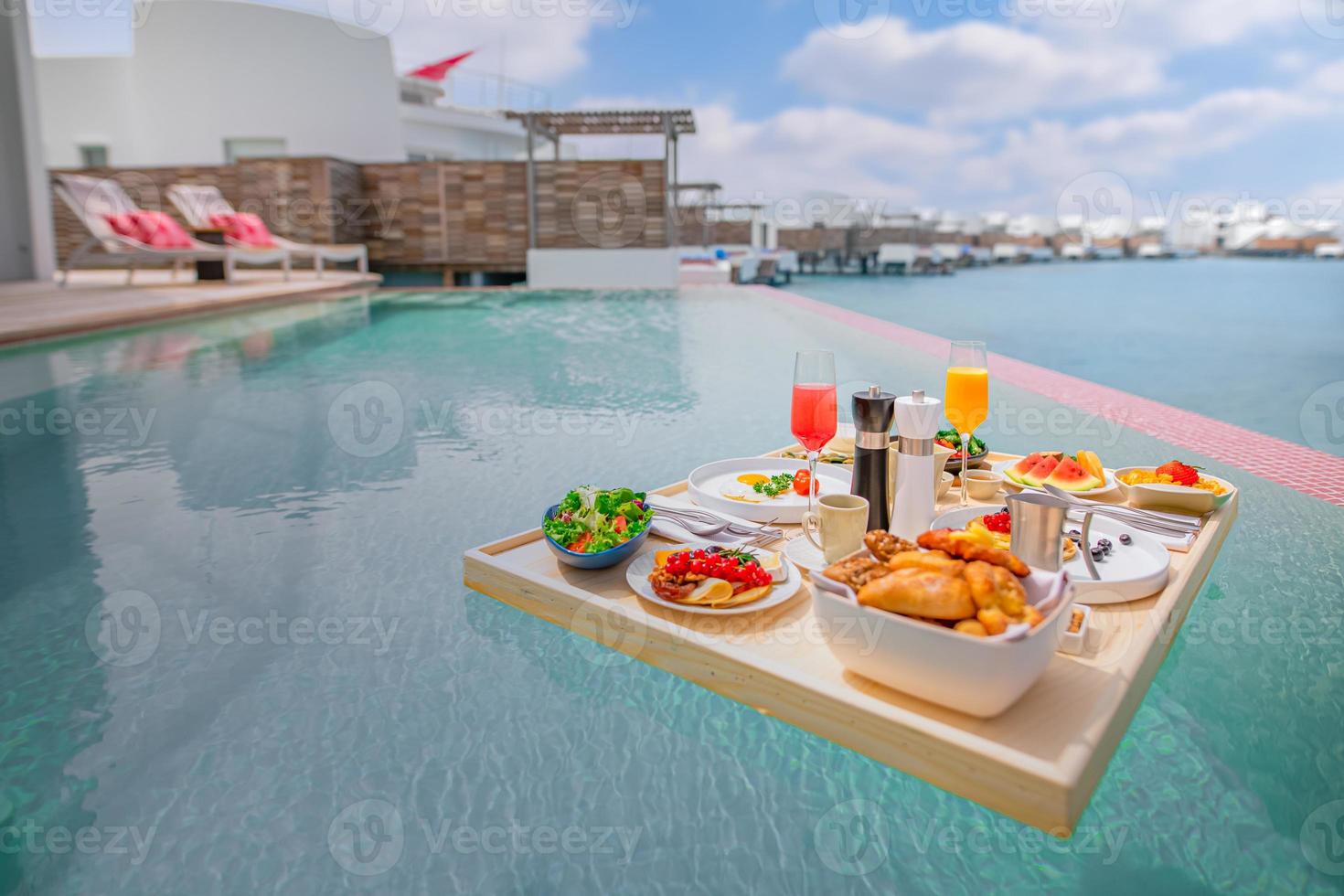 café da manhã na piscina, café da manhã flutuante em luxuoso resort tropical. mesa relaxante na água calma da piscina, café da manhã saudável e prato de frutas na piscina do resort. casal tropical praia luxo estilo de vida foto