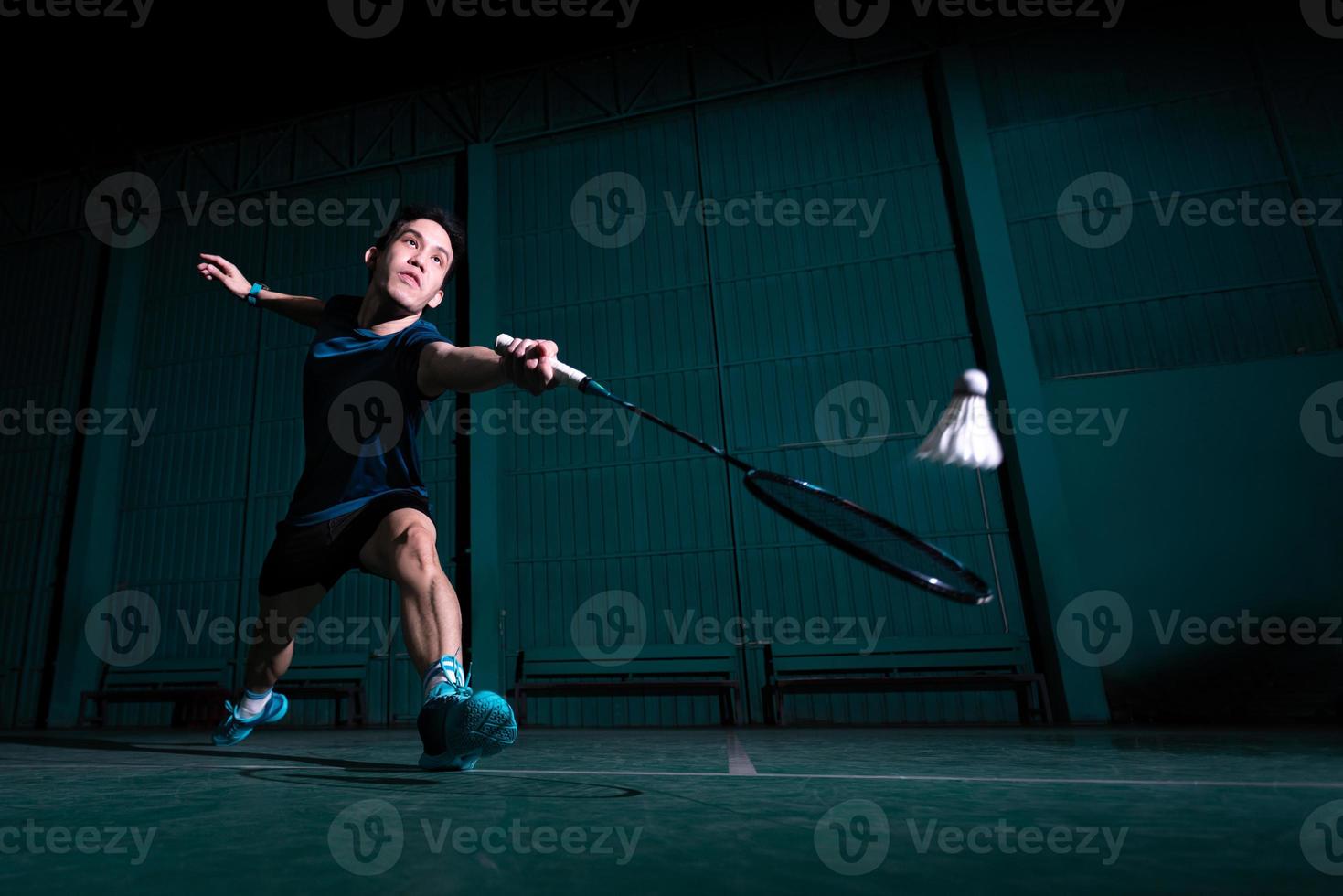 o jogador profissional de badminton usa a raquete com a peteca ou a peteca na quadra durante o aquecimento antes da competição do torneio em um único homem na quadra coberta foto