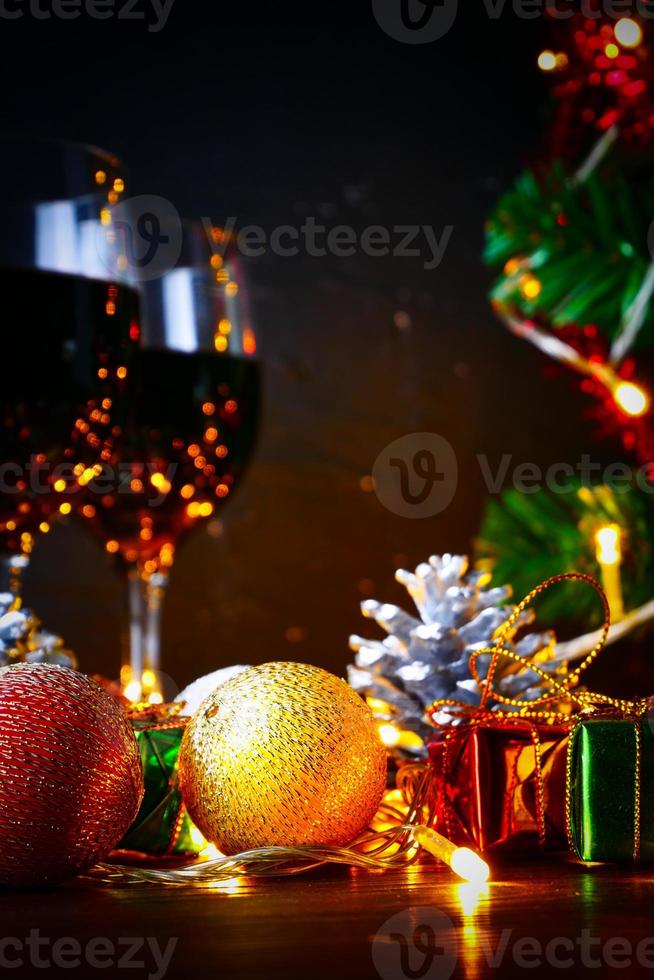 vinho tinto em vidro transparente, árvore de natal e enfeite na mesa de madeira pronta para comemorar. foto