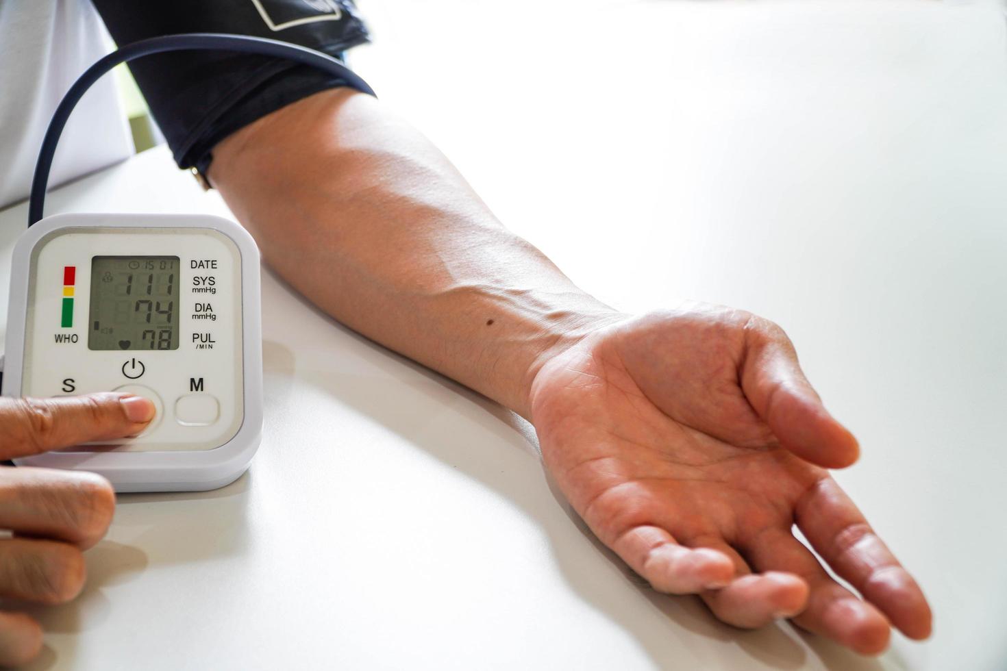 monitoramento da pressão arterial de pacientes usando monitor de pressão arterial de braço na sala de exame clínico. foto