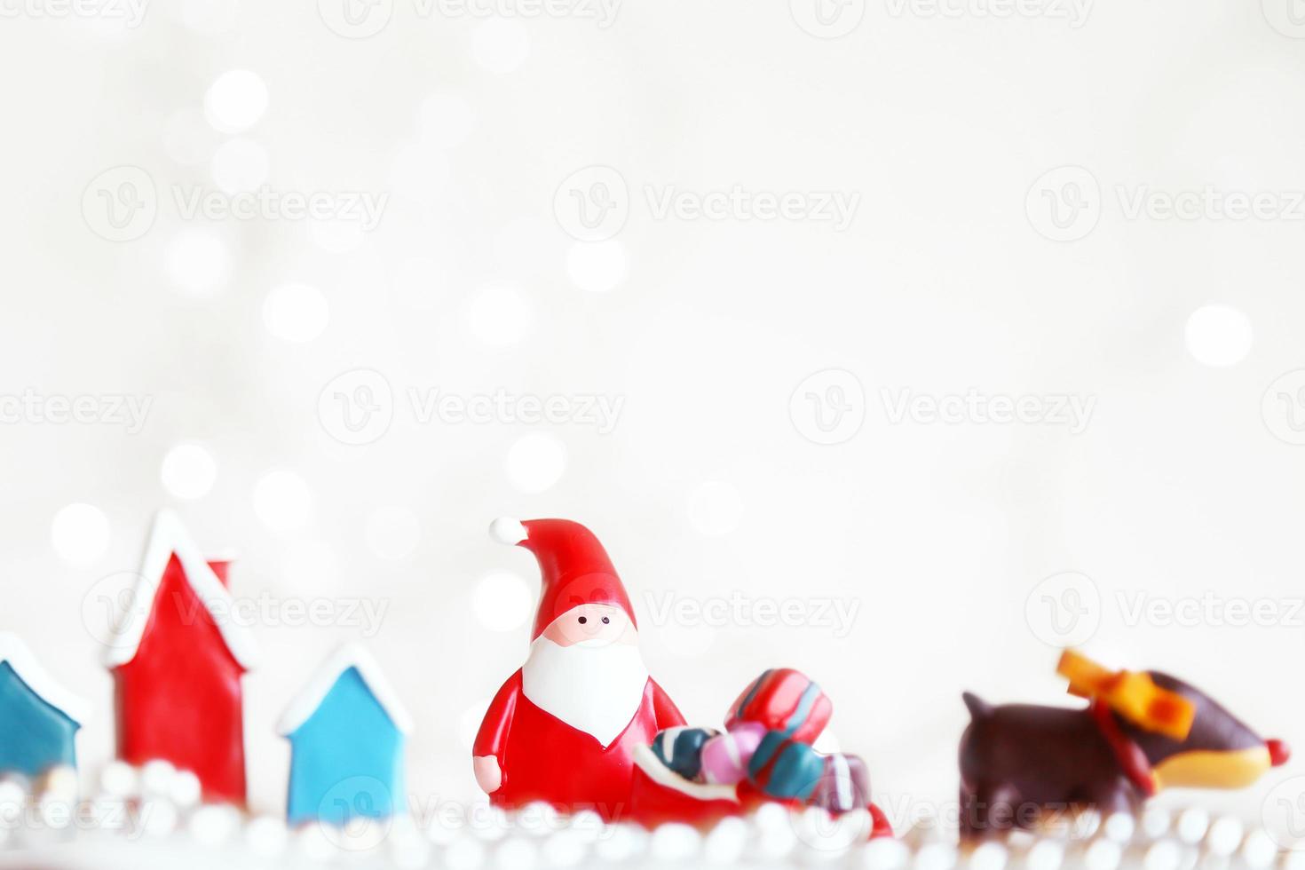 bonecas de papai noel e caixa de decorações de natal em fundo claro abstrato com espaço de cópia foto