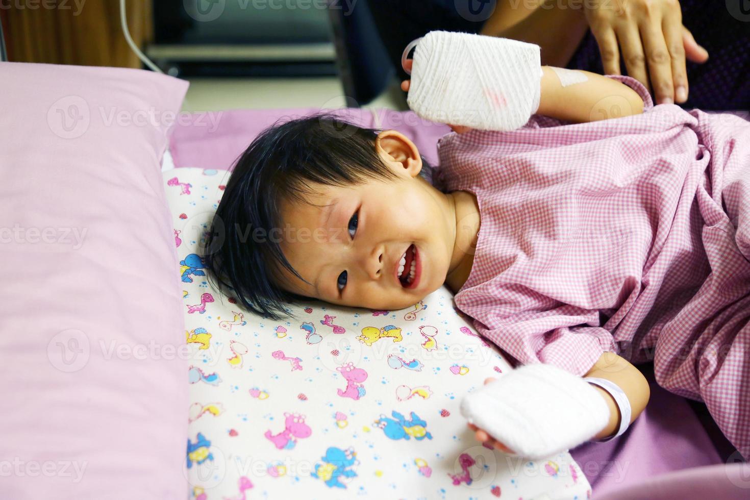 bebê asiático está com febre, em seguida, admitido no hospital e tem tubo iv com almofada nas mãos para proteger a agulha do medicamento. foto