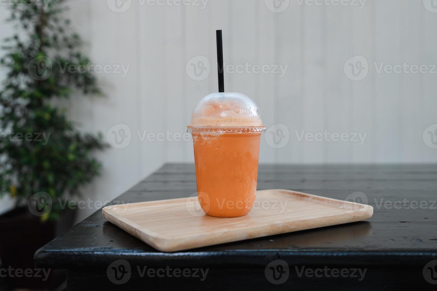 frappe de chá de leite tailandês em copo para viagem na mesa de madeira foto