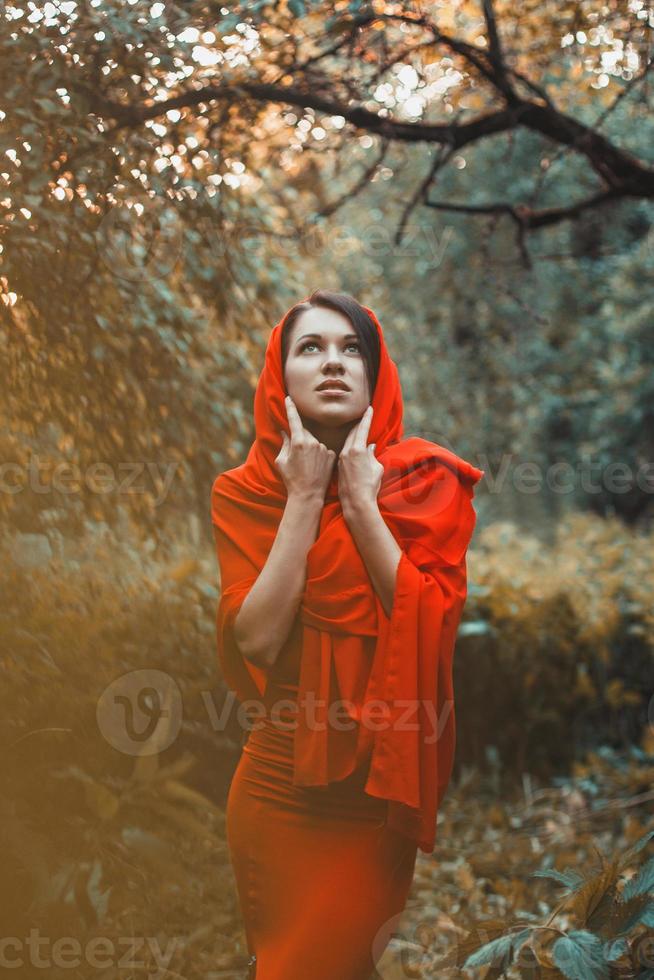 garota fabulosa em um vestido vermelho olhar no jardim foto