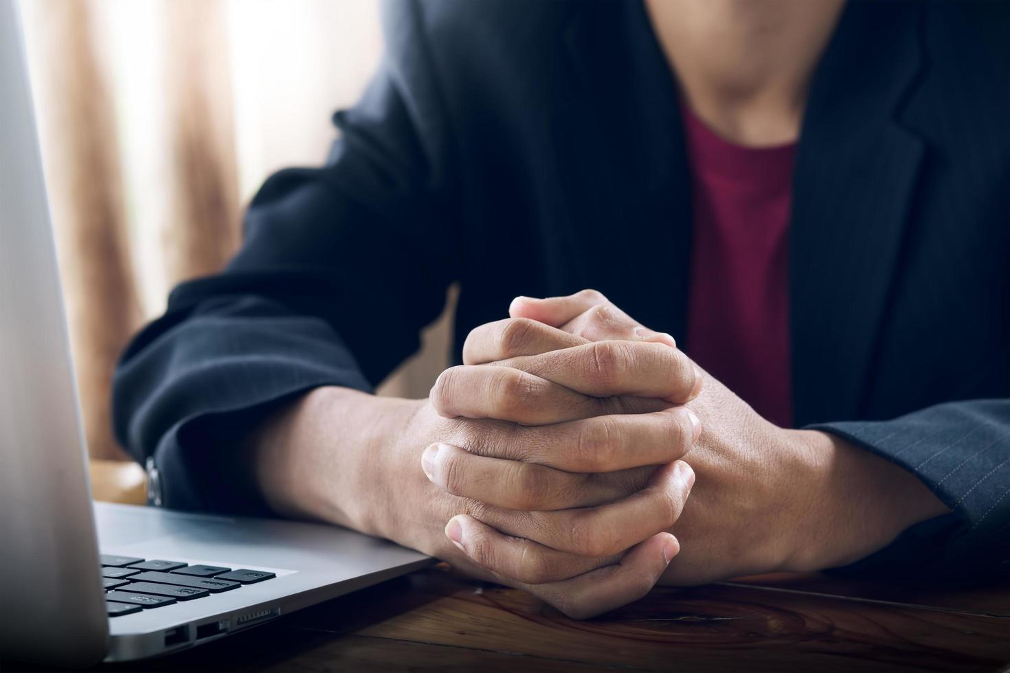 homem orando com computador laptop na mesa de trabalho, orar e adorar no conceito de escritório. foto