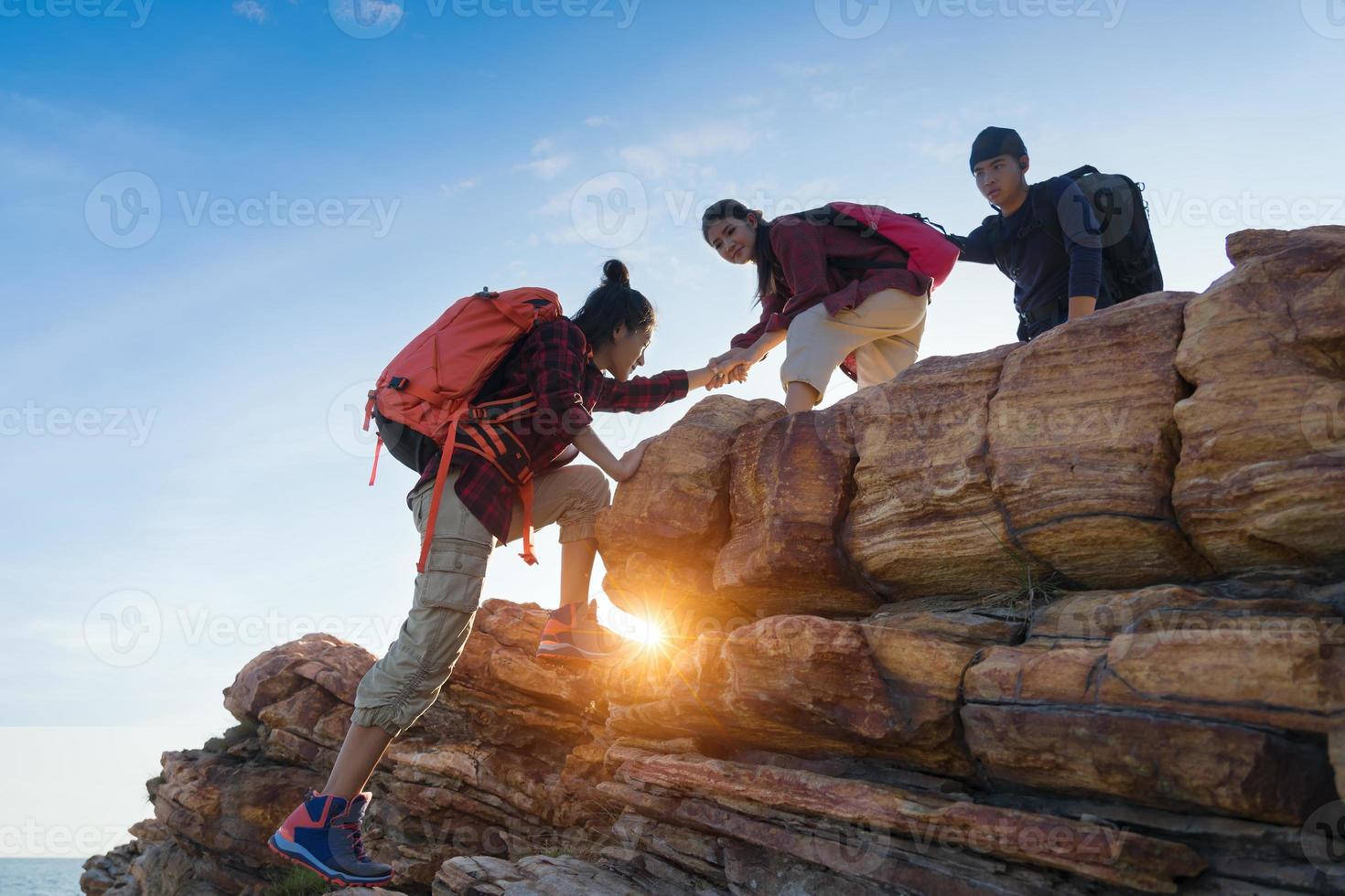 jovem casal asiático subindo na montanha, caminhadas e conceito de trabalho em equipe. foto