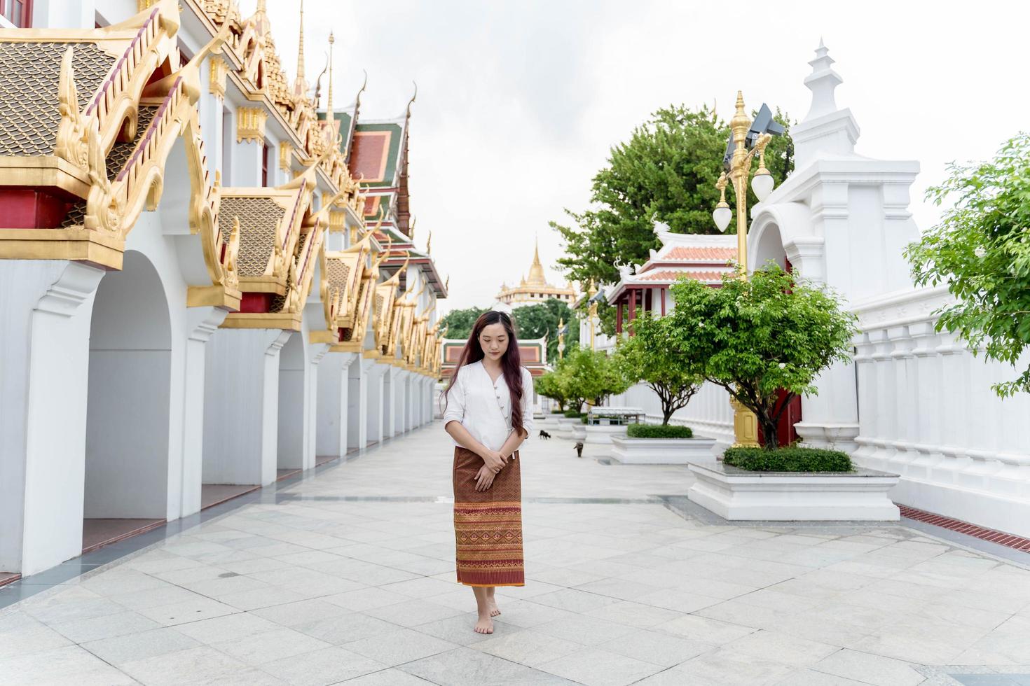 mulher asiática vestindo vestido tradicional da tailândia caminhando meditação ao redor do templo de ratchanatdaram bangkok foto