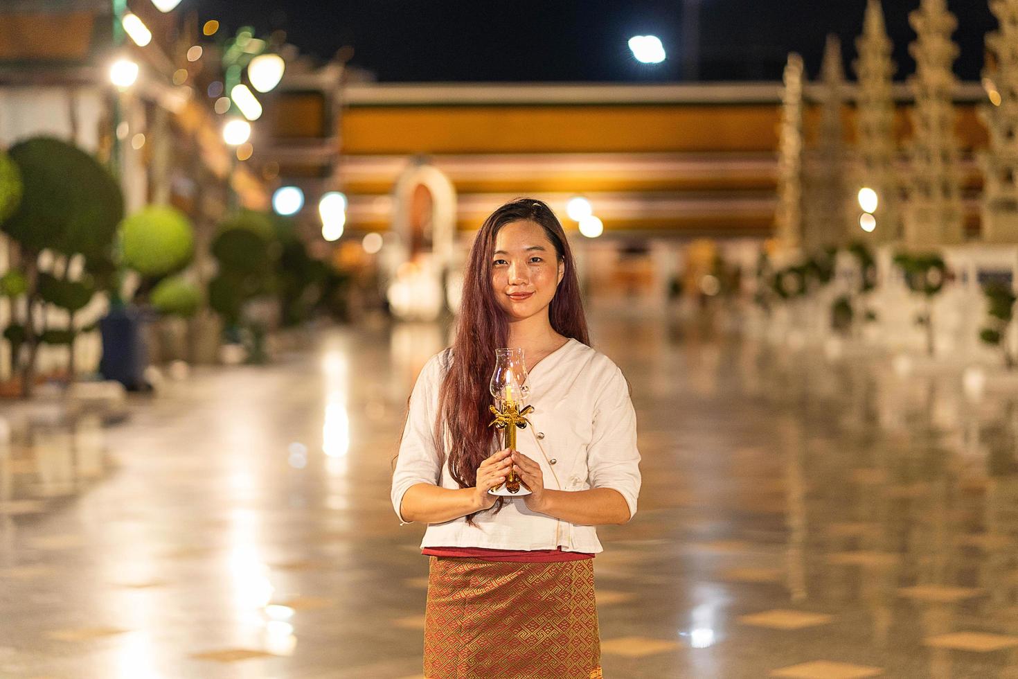 retrato jovem está sorrindo segurando vela em wat suthat thepwararam na noite foto