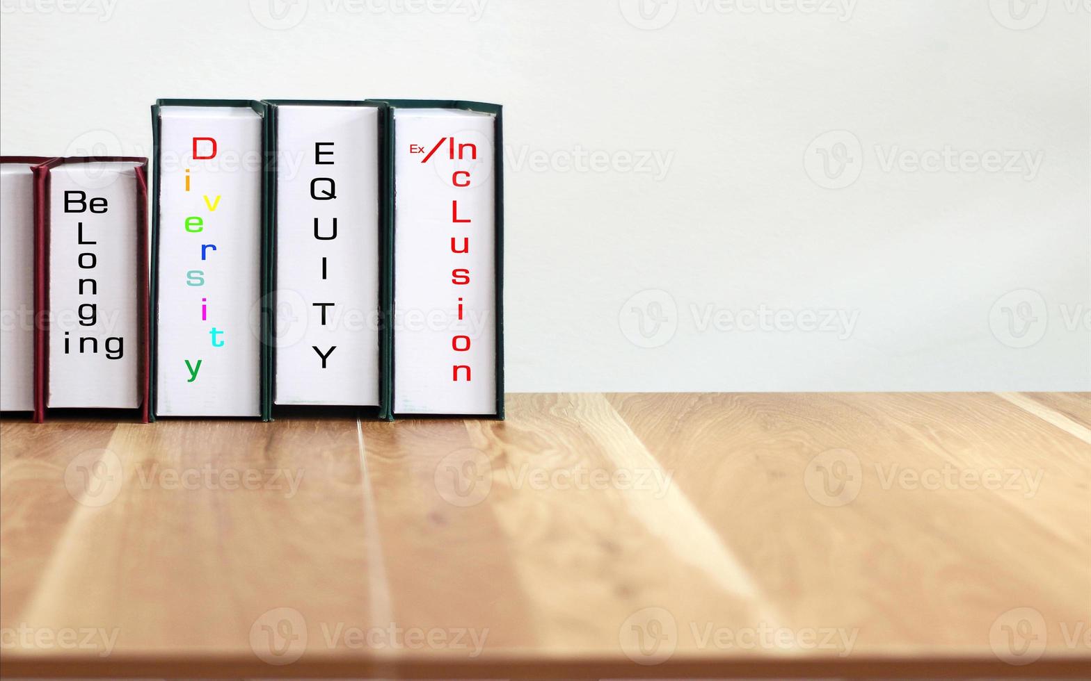livros com palavras dei, diversidade, equidade, inclusão na mesa de madeira com fundo branco. foto