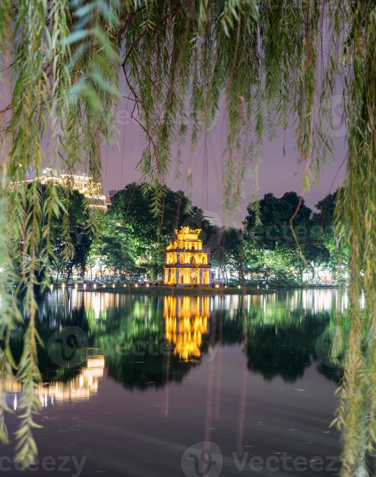 vista da torre da tartaruga através do salgueiro-chorão no lago hoan kiem foto