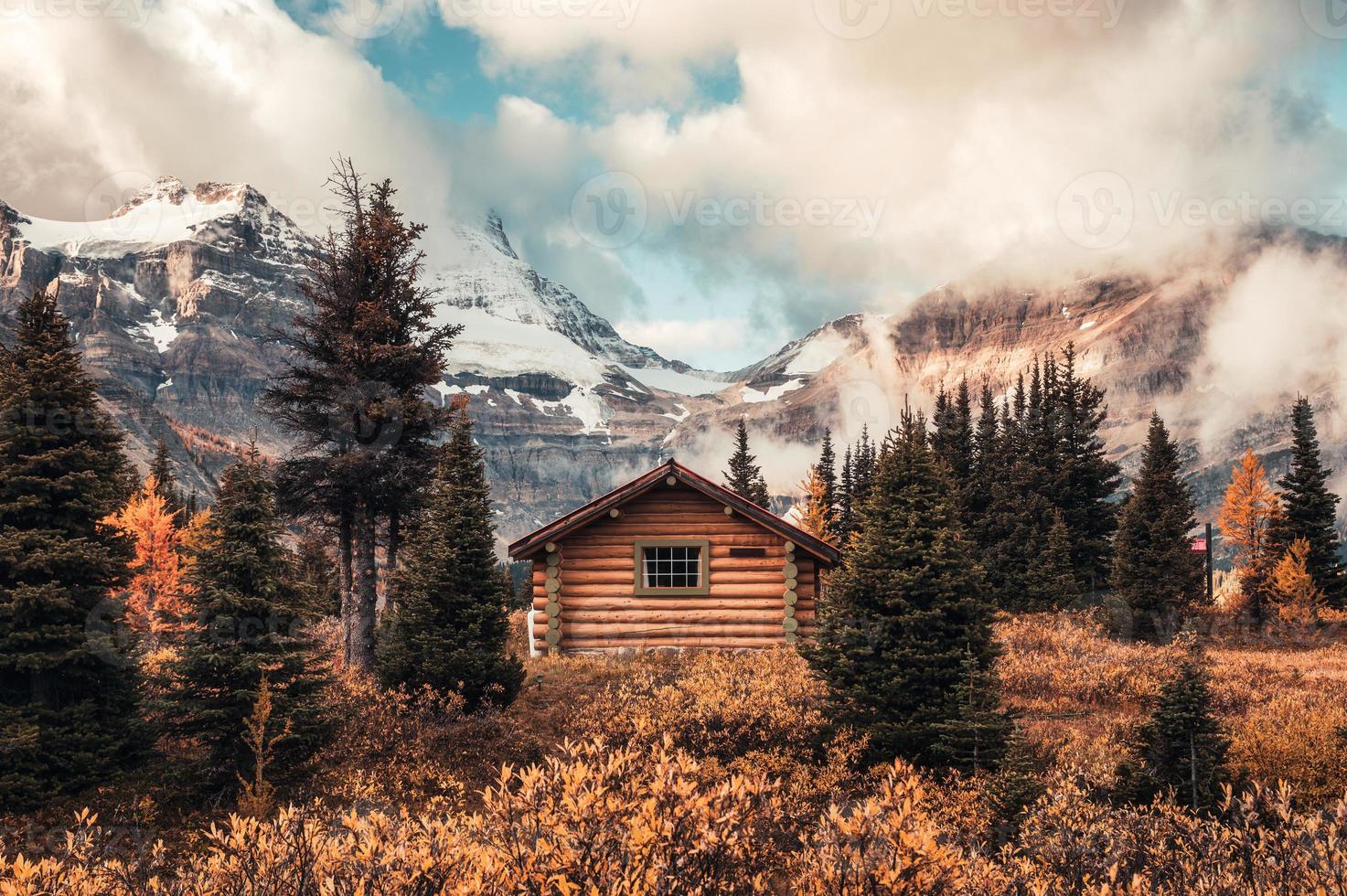 cabana de madeira com montanha assiniboine na floresta de outono no parque provincial foto