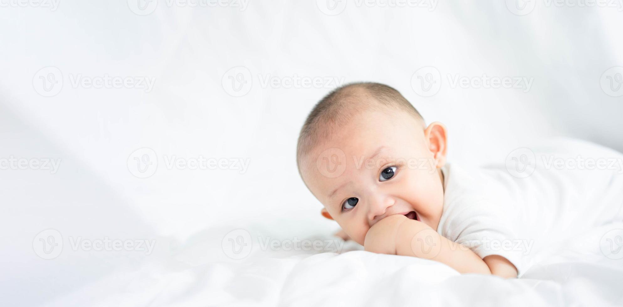 família feliz, bonito bebê recém-nascido asiático deitado jogar na cama branca olhe para a câmera com sorriso sorridente rosto feliz. pequena inocente criança adorável infantil no primeiro dia de vida. conceito de dia das mães. foto