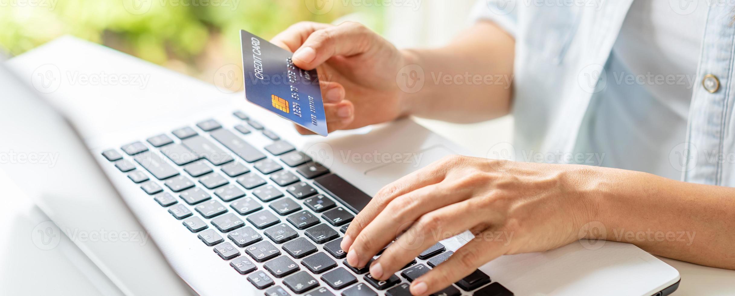 jovem segurando um cartão de crédito e usando o computador para fazer compras de pagamento online foto