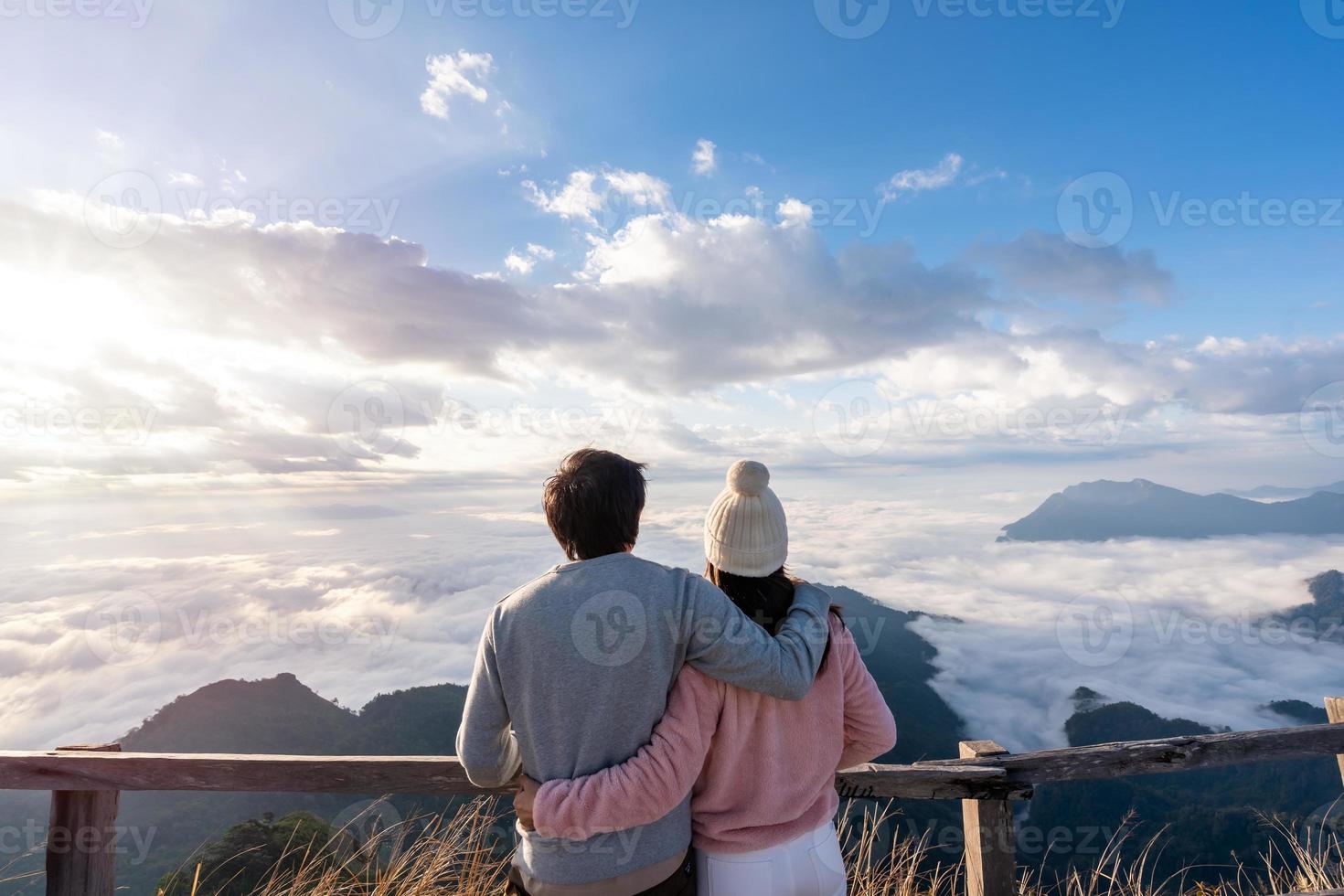 jovem casal viajantes olhando o nascer do sol e o mar de névoa na montanha pela manhã, conceito de estilo de vida de viagem foto
