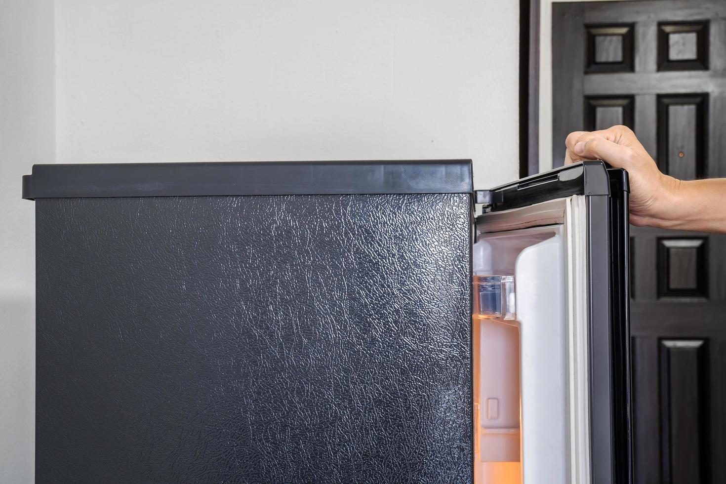 a mão de um jovem está abrindo uma porta de freezer no hotel foto