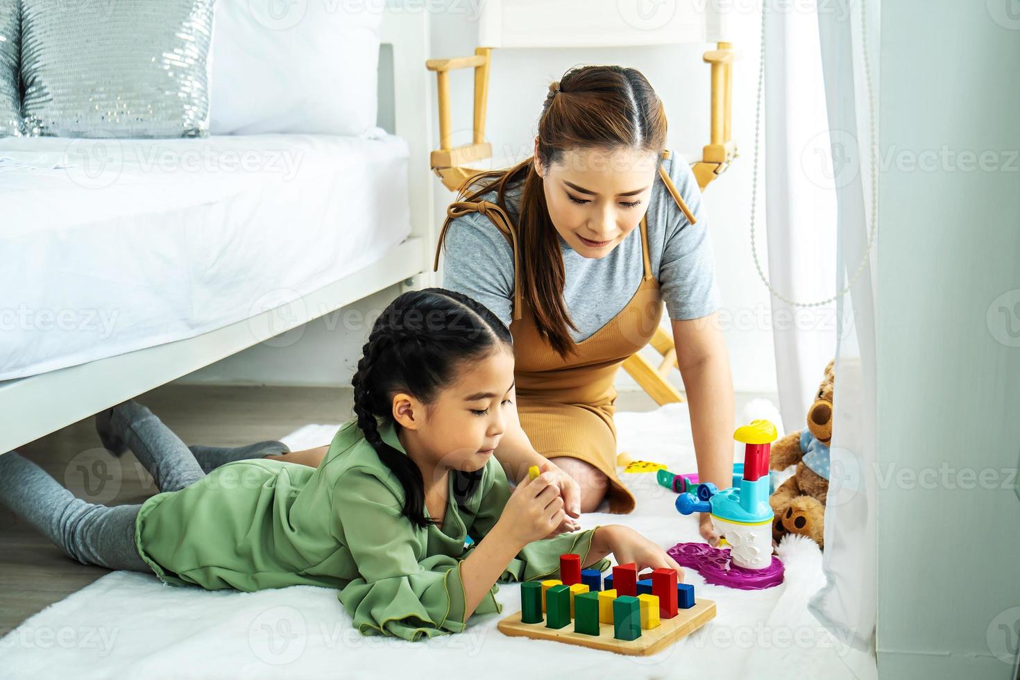 feliz mãe asiática e menina asiática jogando brinquedos educativos no chão do quarto. atividades domésticas para a família. foto