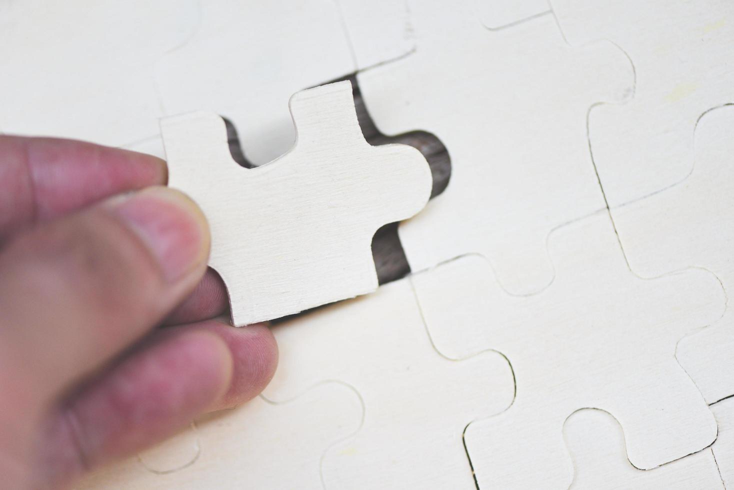 homem de negócios segurando quebra-cabeça - close-up de peças de quebra-cabeça para juntar e tentar conectar o conceito de parceria de negócios foto