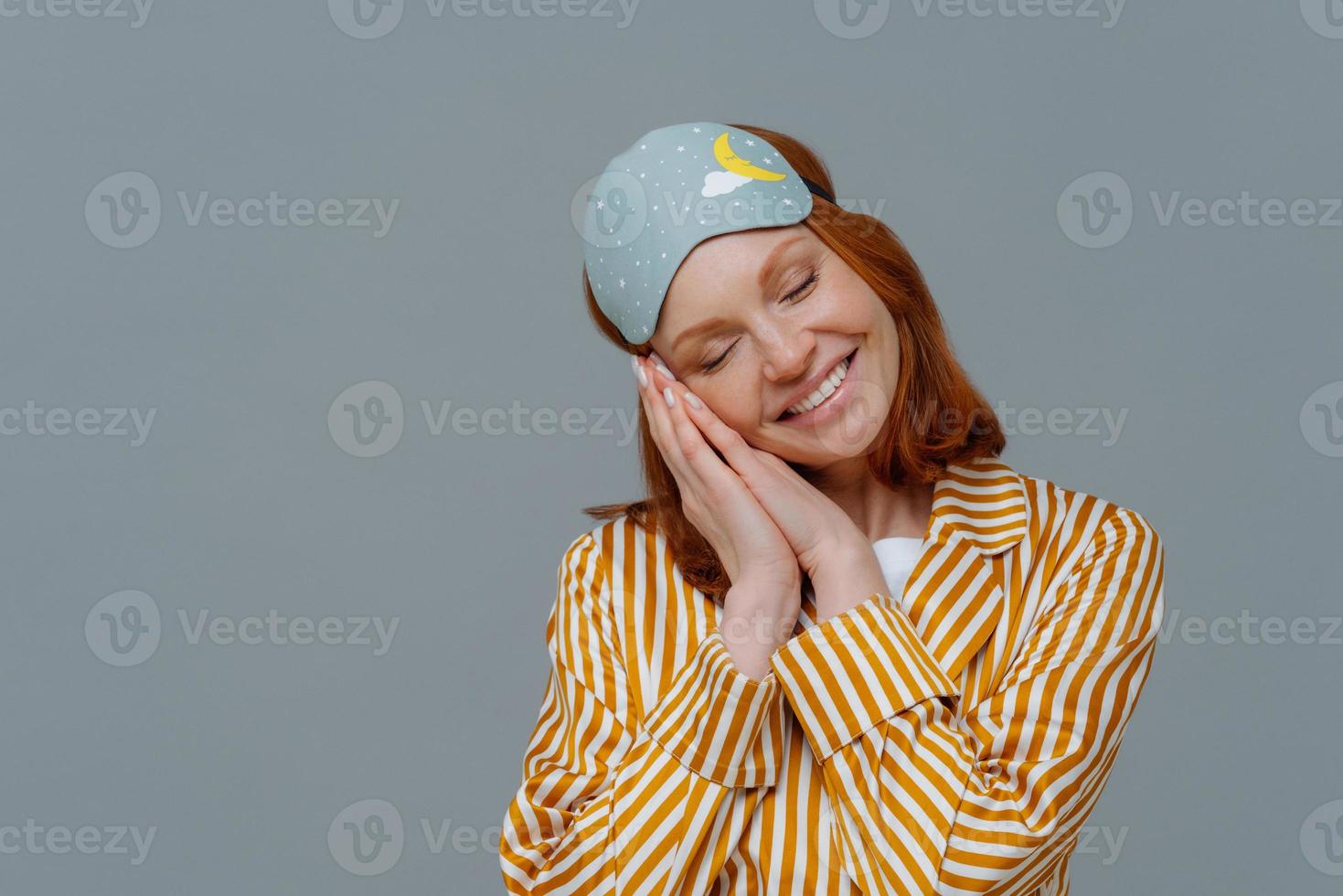 sono profundo e prazer. mulher bonita sardenta inclina a cabeça, sorri amplamente, mostra dentes brancos, usa roupas domésticas e venda, tem sonhos agradáveis, tem um bom dia, não quer acordar foto