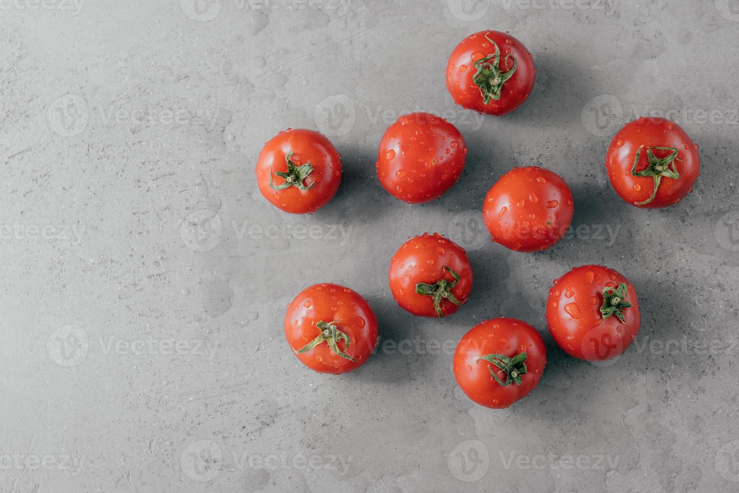 deliciosos tomates vermelhos para fazer ketchup em fundo cinza. legumes cobertos com gotas de água. conceito de frescura e nutrição. tiro horizontal foto