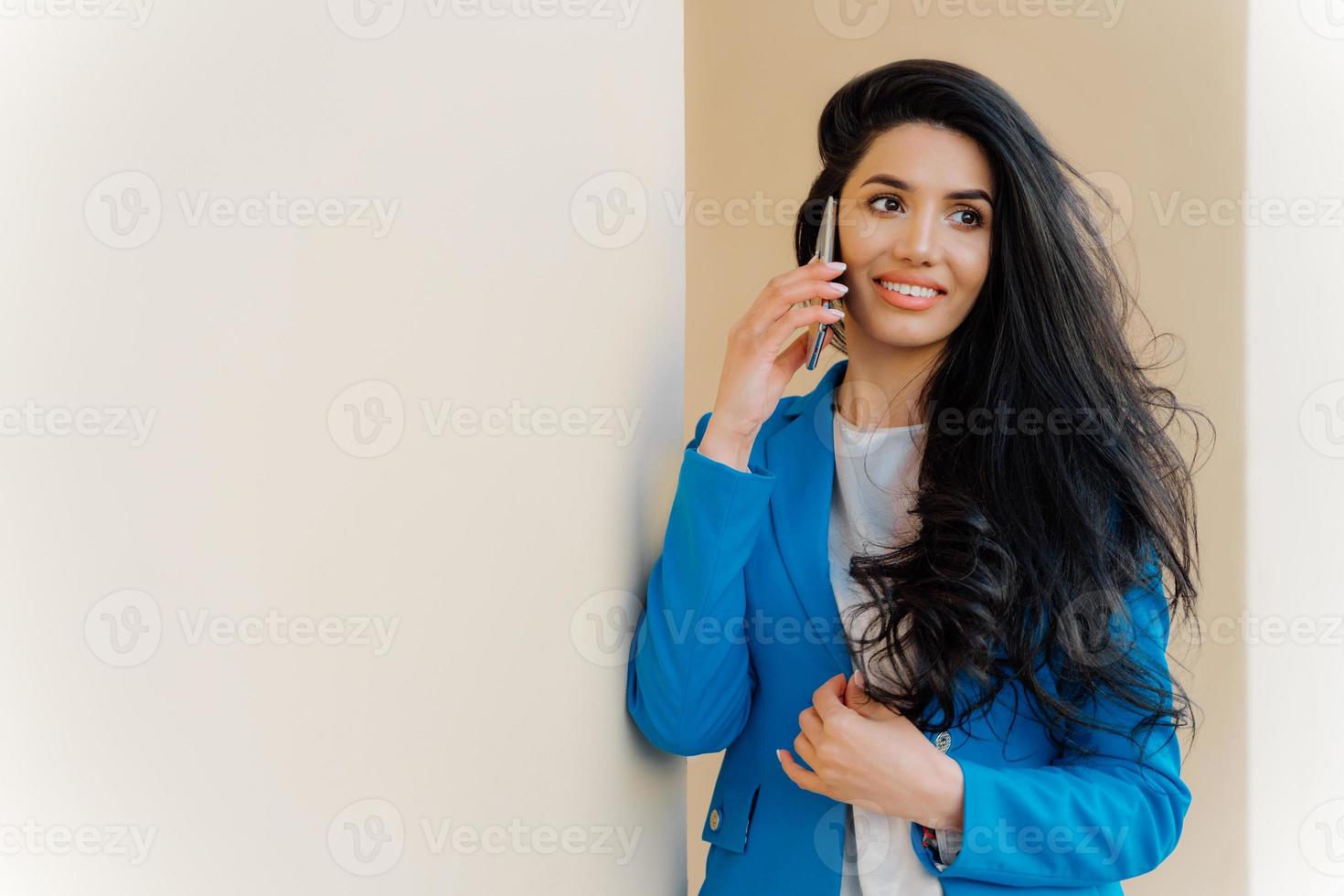 alegre empresária europeia fala sobre suas conquistas, gosta de boas notícias no trabalho, usa elegante jaqueta azul, parece alegremente de lado. funcionária feliz se alegra com a prosperidade da carreira, usa celular foto