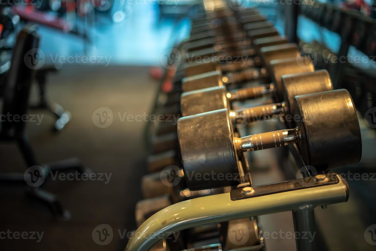 conjunto de halteres preto. feche muitos halteres de metal no rack no centro de fitness esportivo, conceito de equipamento de treinamento com pesos. foto