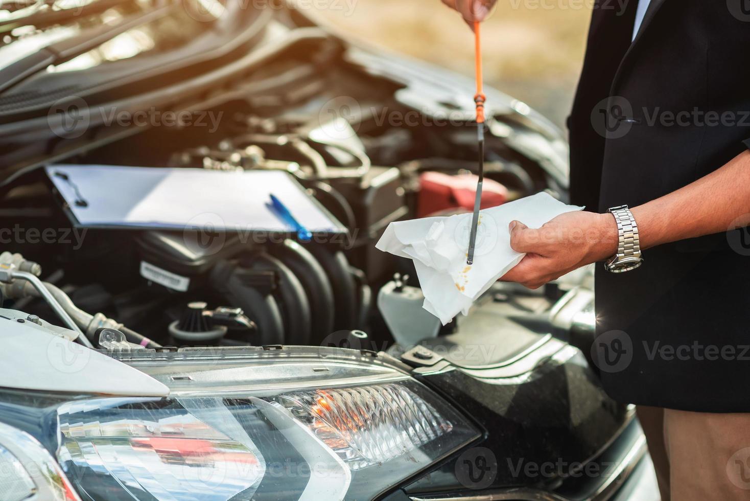 mecânico reparando carro com capô aberto, vista lateral do mecânico verificando nível de óleo do motor em um carro com capô aberto foto