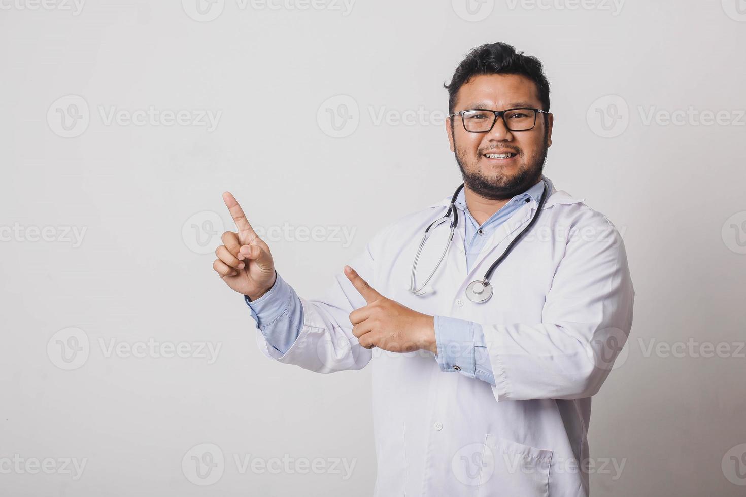 alegre médico masculino com gesto de apontar lateralmente no espaço de cópia isolado no fundo branco foto