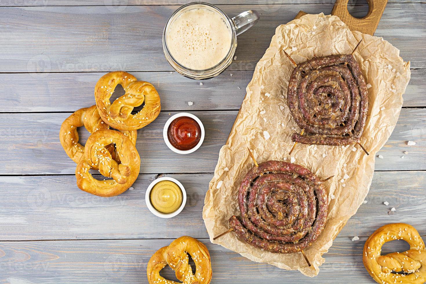 menu de comida para oktoberfest. salsicha com molho diferente, pretzel e copo de cerveja escura foto