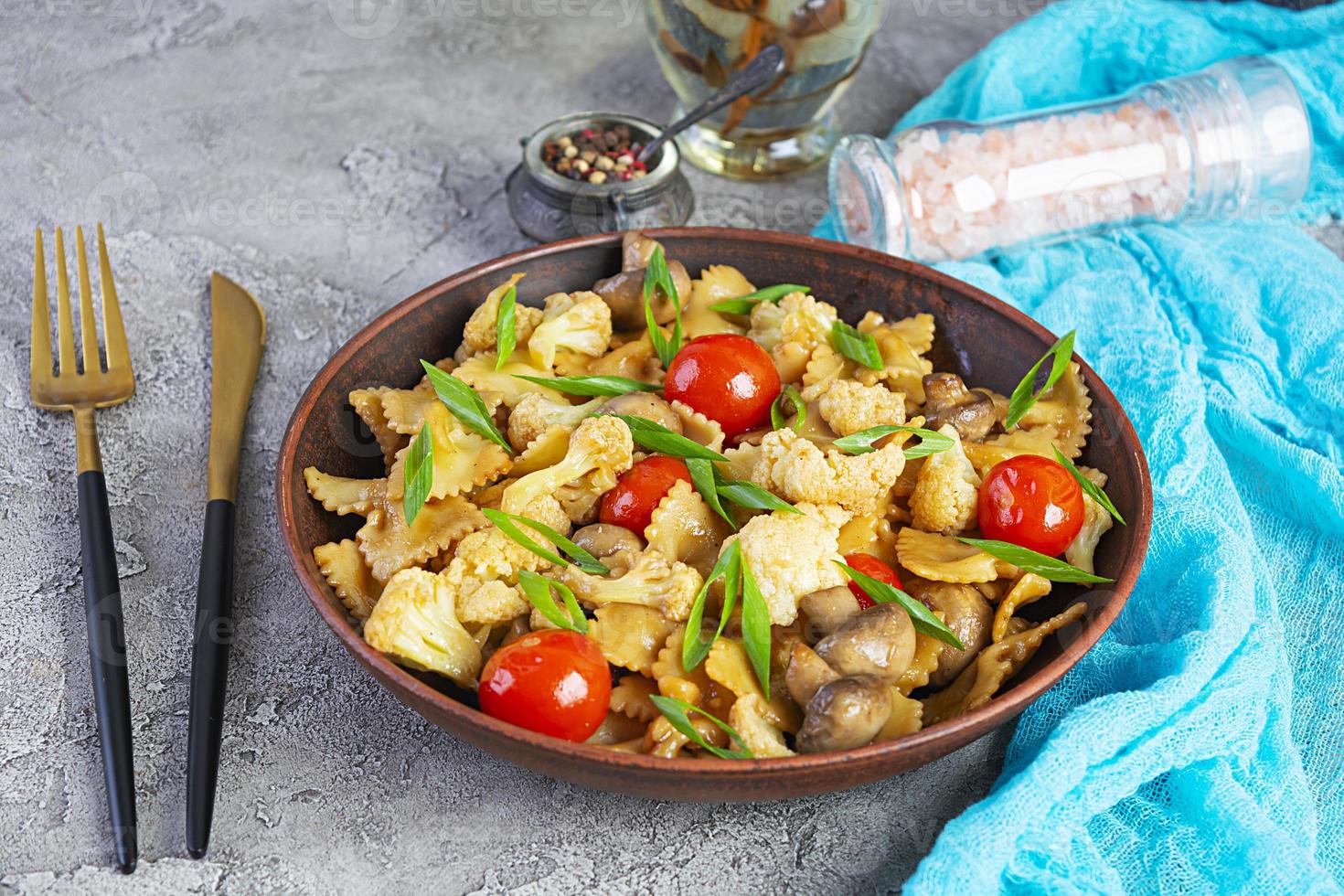 frite a massa farfalle com legumes, couve-flor e cogumelos foto