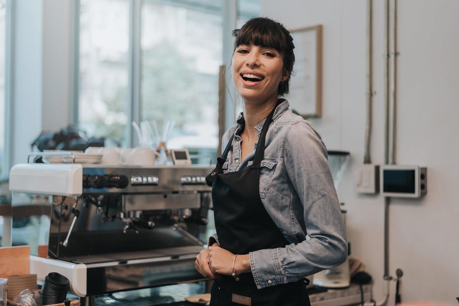 mulher feliz dono de café atrás do balcão de uma cafeteria. barista feminino em pé atrás do balcão no café. conceito de empresário. foto