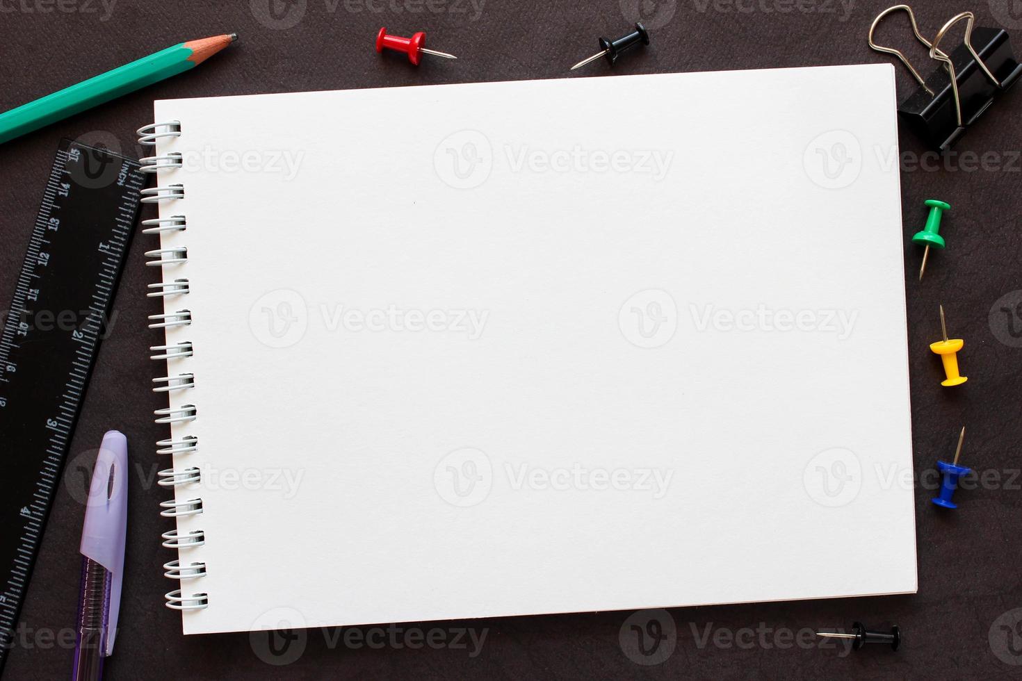 bloco de notas em branco para o seu texto. ao redor do notebook são material de escritório. foto