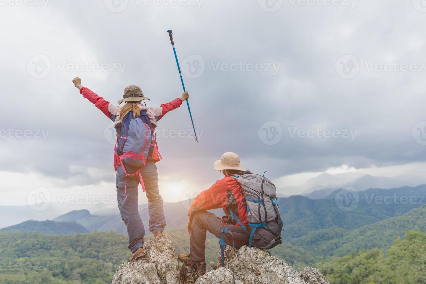 alpinistas ativos apreciam a paisagem. mochileiros masculinos e femininos com mochilas e muletas no topo de uma montanha. foto