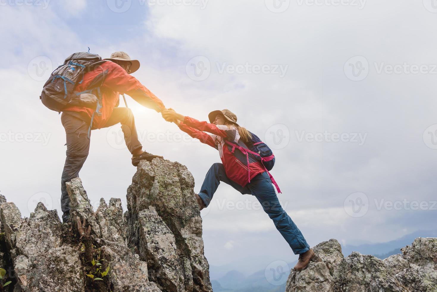 jovem casal viajando, mão amiga, mulher alpinista recebendo ajuda na caminhada sorrindo feliz superando obstáculo, mochileiros turísticos andando na floresta. foto