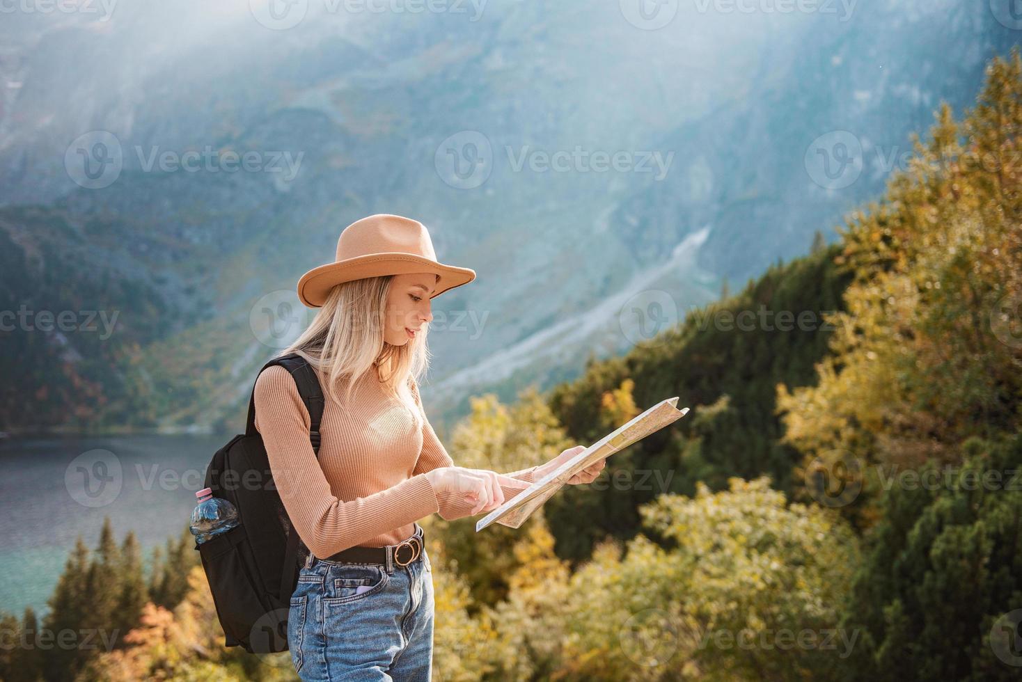 desejo de viajar e conceito de viagem. garota elegante viajante de chapéu olhando para o mapa, explorando a floresta. foto