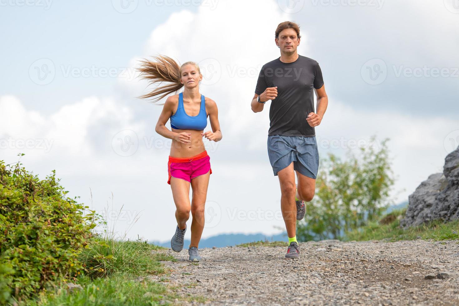 casal de jovens atletas corre na estrada de terra. foto