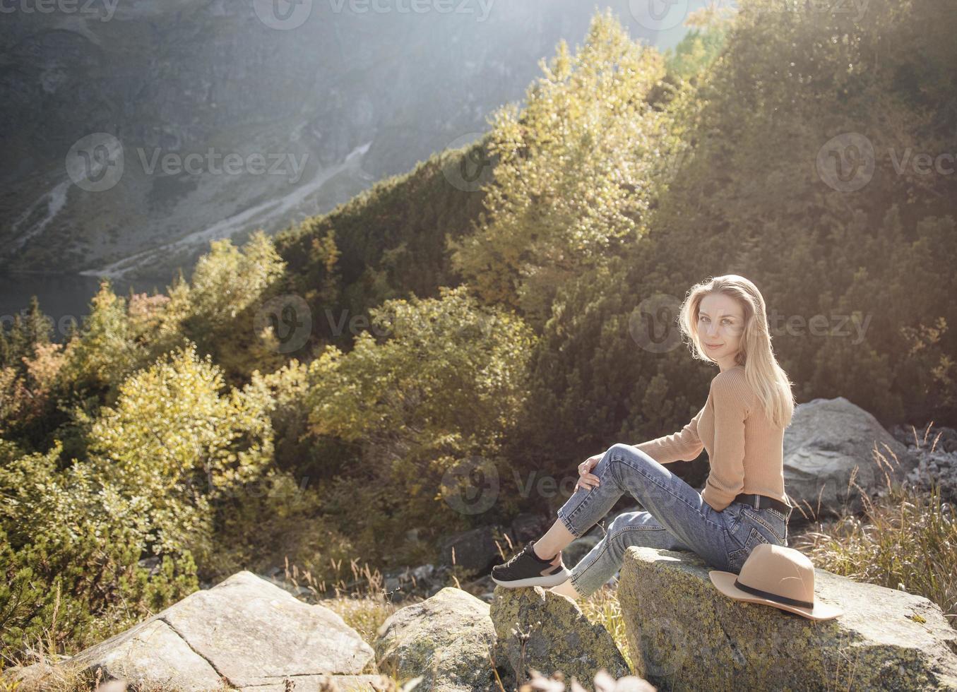 jovem mulher em uma caminhada sentado em uma pedra foto