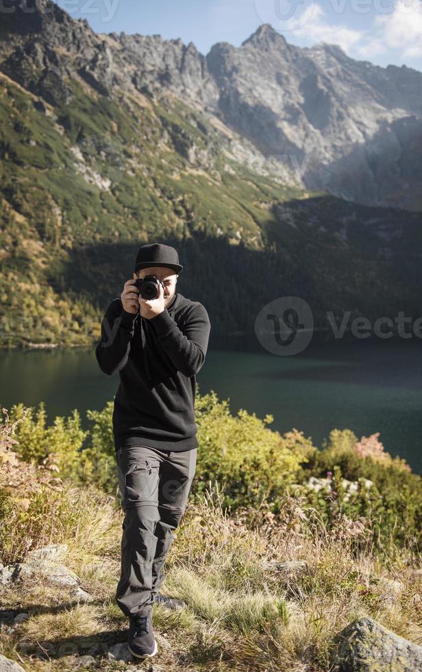 jovem fotógrafo tirando fotografias com câmera digital em montanhas. foto