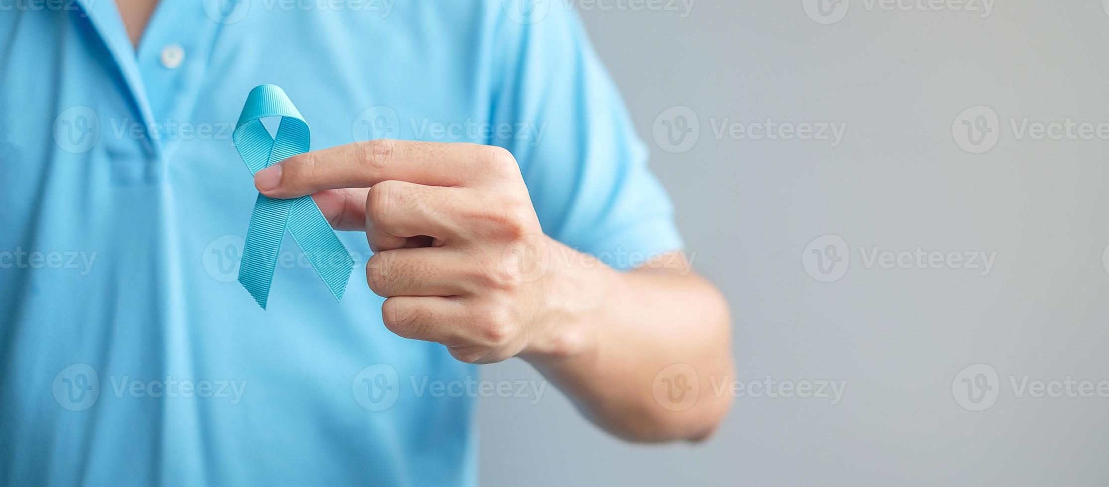 mês de conscientização do câncer de próstata de novembro, homem de camisa azul com a mão segurando a fita azul para apoiar as pessoas que vivem e estão doentes. cuidados de saúde, homens internacionais, pai e conceito de dia mundial do câncer foto