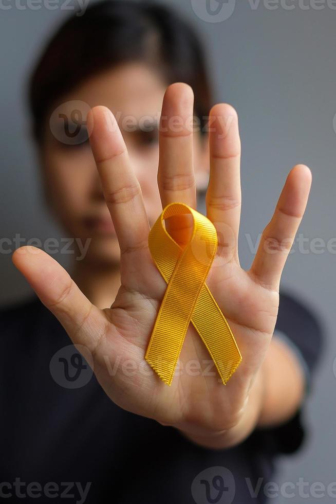 dia de prevenção do suicídio, sarcoma, osso, bexiga e mês de conscientização do câncer infantil, fita amarela para apoiar as pessoas que vivem e estão doentes. saúde infantil e conceito de dia mundial do câncer foto