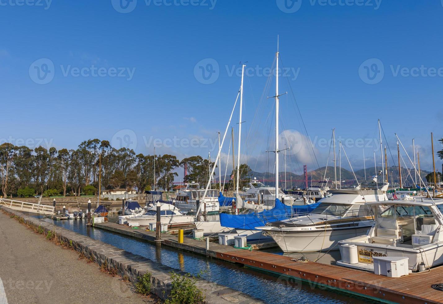 vista da marina com iates ancorados em primeiro plano, no fundo ponte golden gate em nuvens pequenas e bonitas, califórnia, eua foto