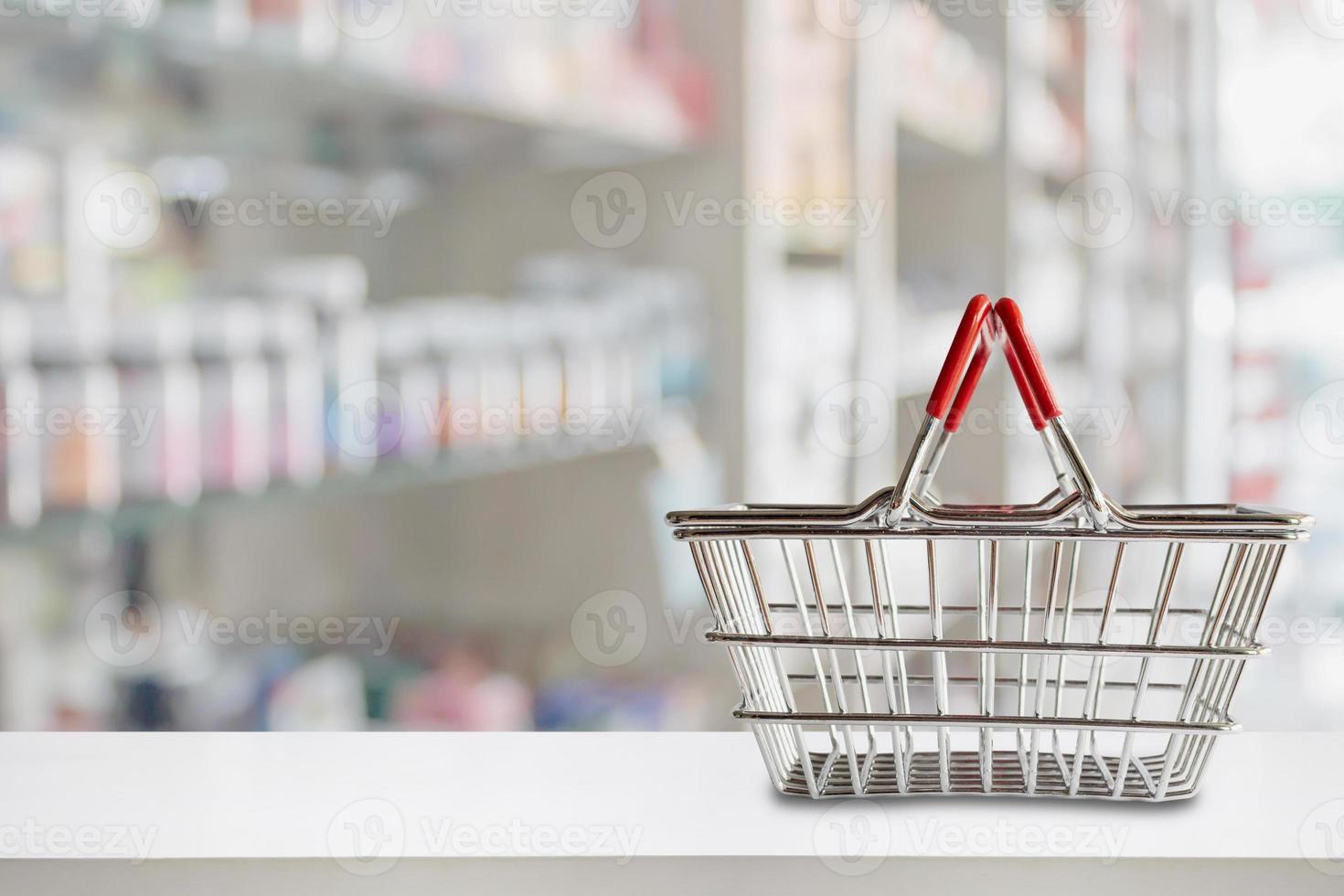cesto de compras vazio no balcão da farmácia com prateleiras desfocadas de fundo de medicamentos e suplementos vitamínicos foto